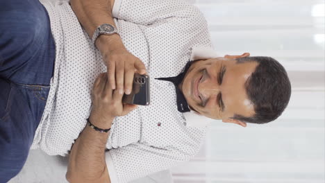 Vertical-video-of-Man-smiling-at-phone-message.